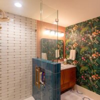 Thumbnail of http://Renovated%20bathroom%20with%20white%20and%20blue%20tiles%20in%20the%20shower,%20gold%20fixtures,%20and%20a%20wallpaper%20that%20features%20peacocks.