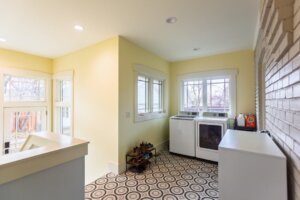 Laundry room, mudroom with Craftsman style windows, geometric tile, yellow walls, and a washer and dryer