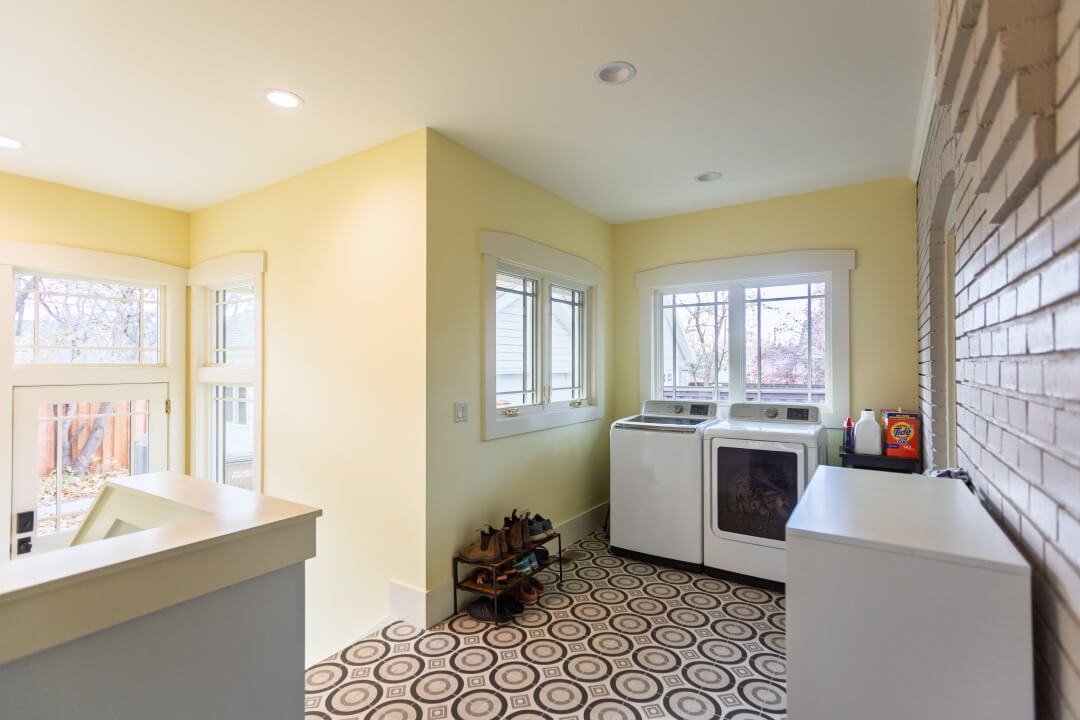 Laundry room, mudroom with Craftsman style windows, geometric tile, yellow walls, and a washer and dryer