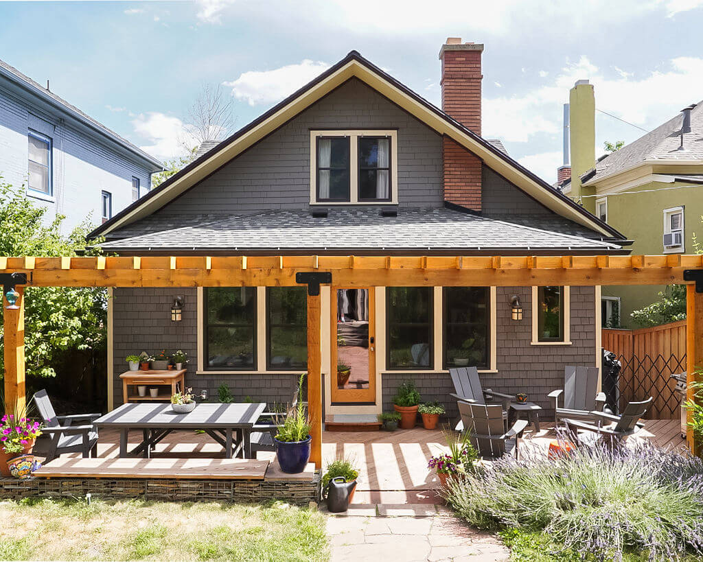 Backyard of bungalow style home with a large pergola and patio area.