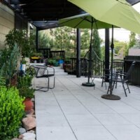 Thumbnail of http://Large%20outdoor%20patio%20with%20a%20few%20plants,%20chairs,%20and%20umbrellas.
