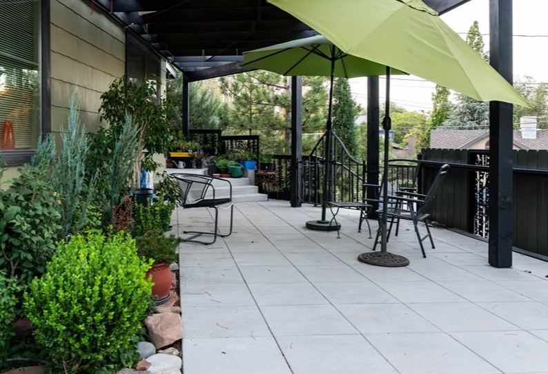 Large outdoor patio with a few plants, chairs, and umbrellas.
