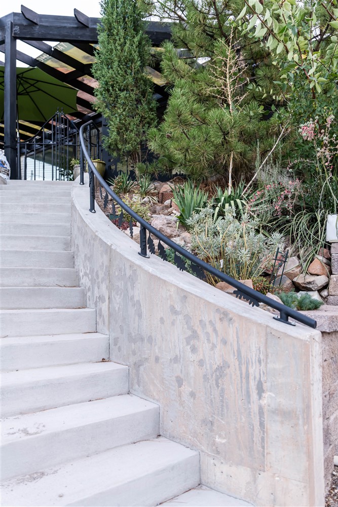 Exterior staircase leading from the driveway up to the front door and new patio. The concrete stairs are slightly curved and include a metal railing.