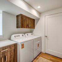 Thumbnail of http://Side-by-side%20washer%20and%20dryer%20with%20cabinet%20above,%20counter%20adjacent%20with%20a%20window%20above,%20and%20a%20door%20on%20the%20wall.