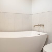 Thumbnail of http://Bath%20tub%20next%20to%20the%20toilet%20with%20tile%20up%20a%20portion%20of%20the%20wall.