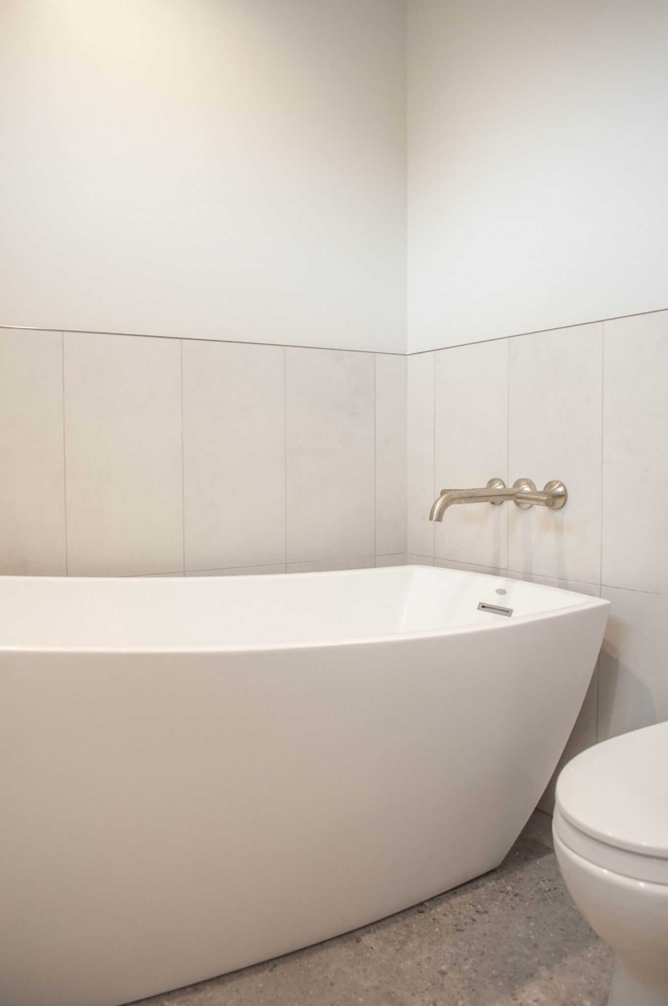 Bath tub next to the toilet with tile up a portion of the wall.