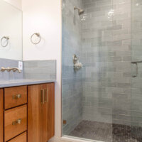 Thumbnail of http://Modern%20bathroom%20vanity%20and%20shower.%20The%20sink%20includes%20a%20wall-mounted%20faucet%20with%20a%20mirror%20above.%20The%20shower%20has%20a%20glass%20door%20and%20bench%20seat%20built-in.