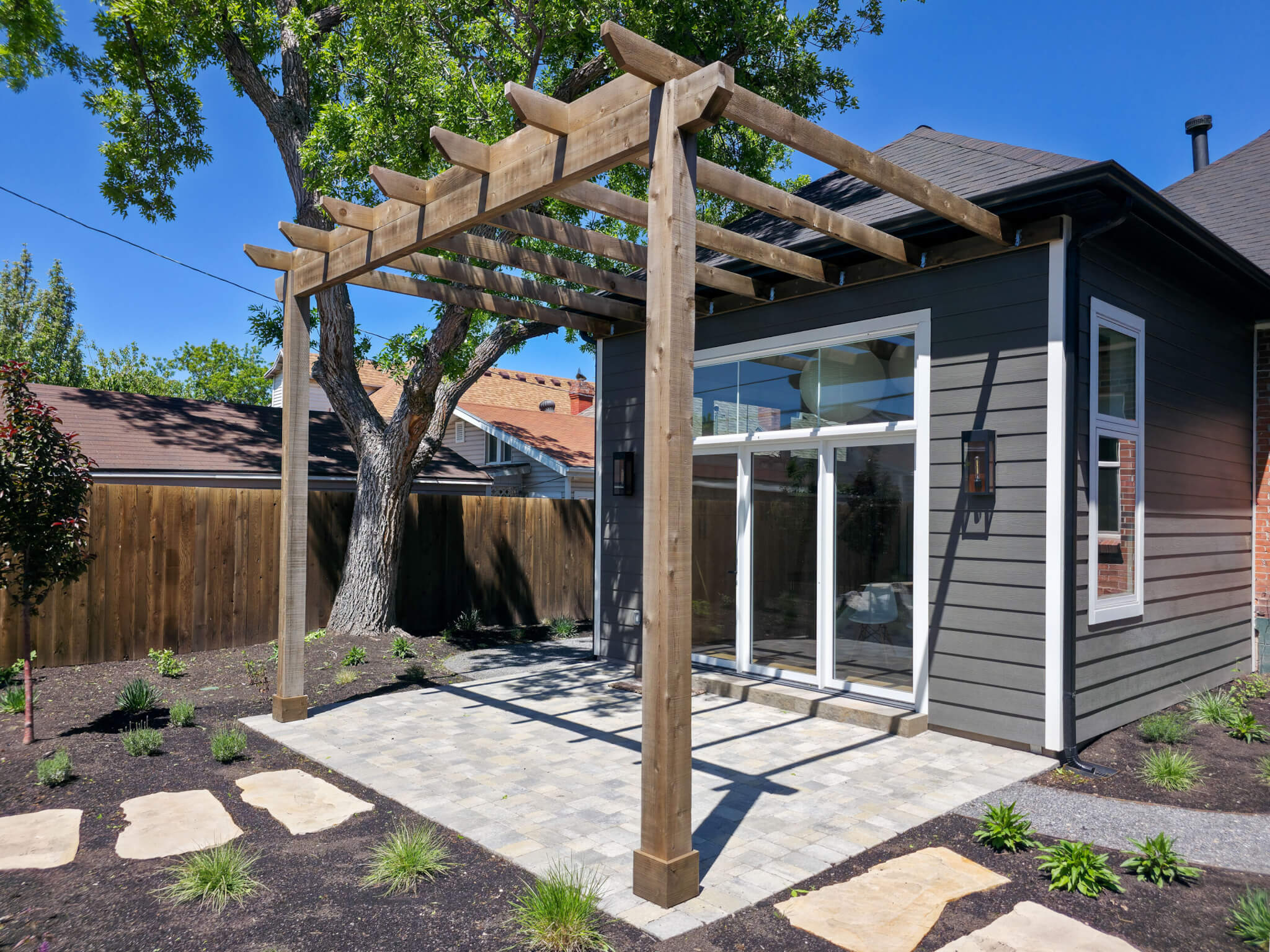 Exterior of the addition featuring the large windows and patio with a pergola.