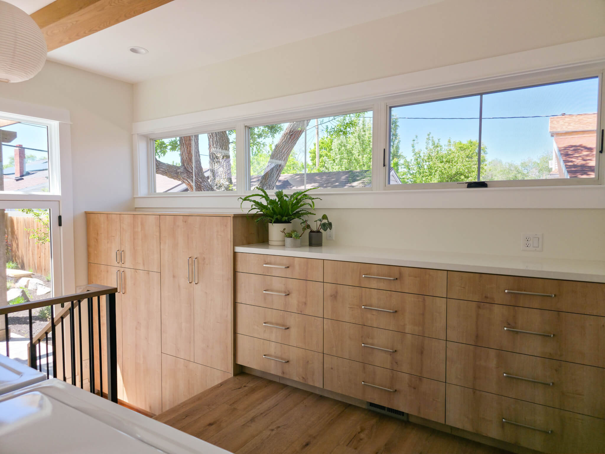 Built-in cabinets in the laundry room that extend down the stairs to in the mudroom. Above the cabinets are windows.