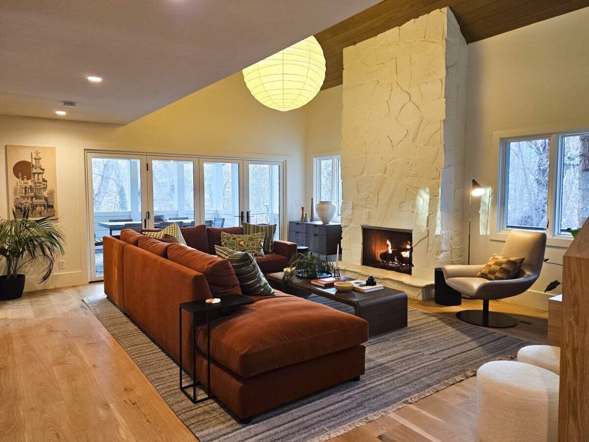 Living room with large couch, fireplace, and natural light from the windows.