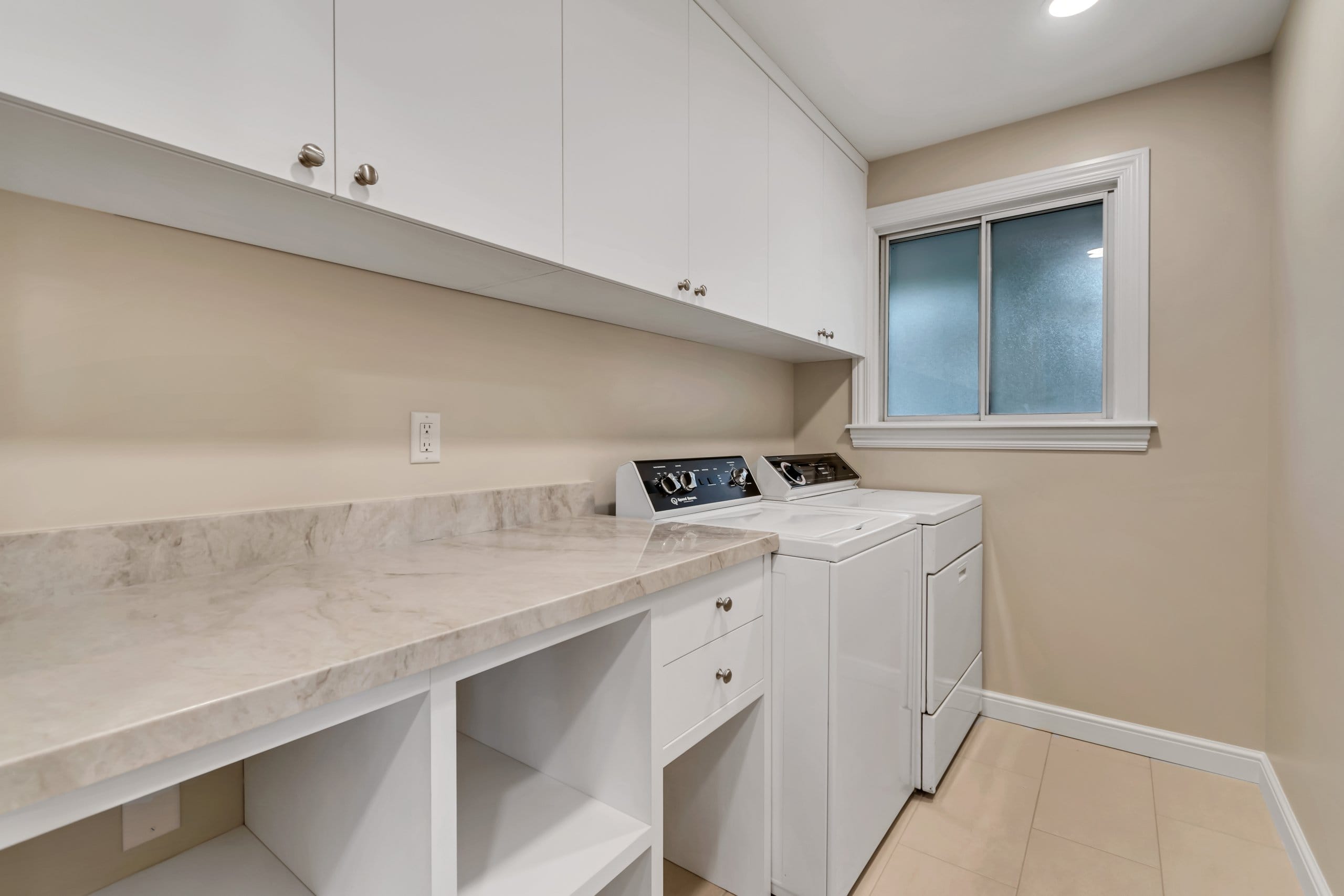 Laundry room with white cabinetry and appliances.