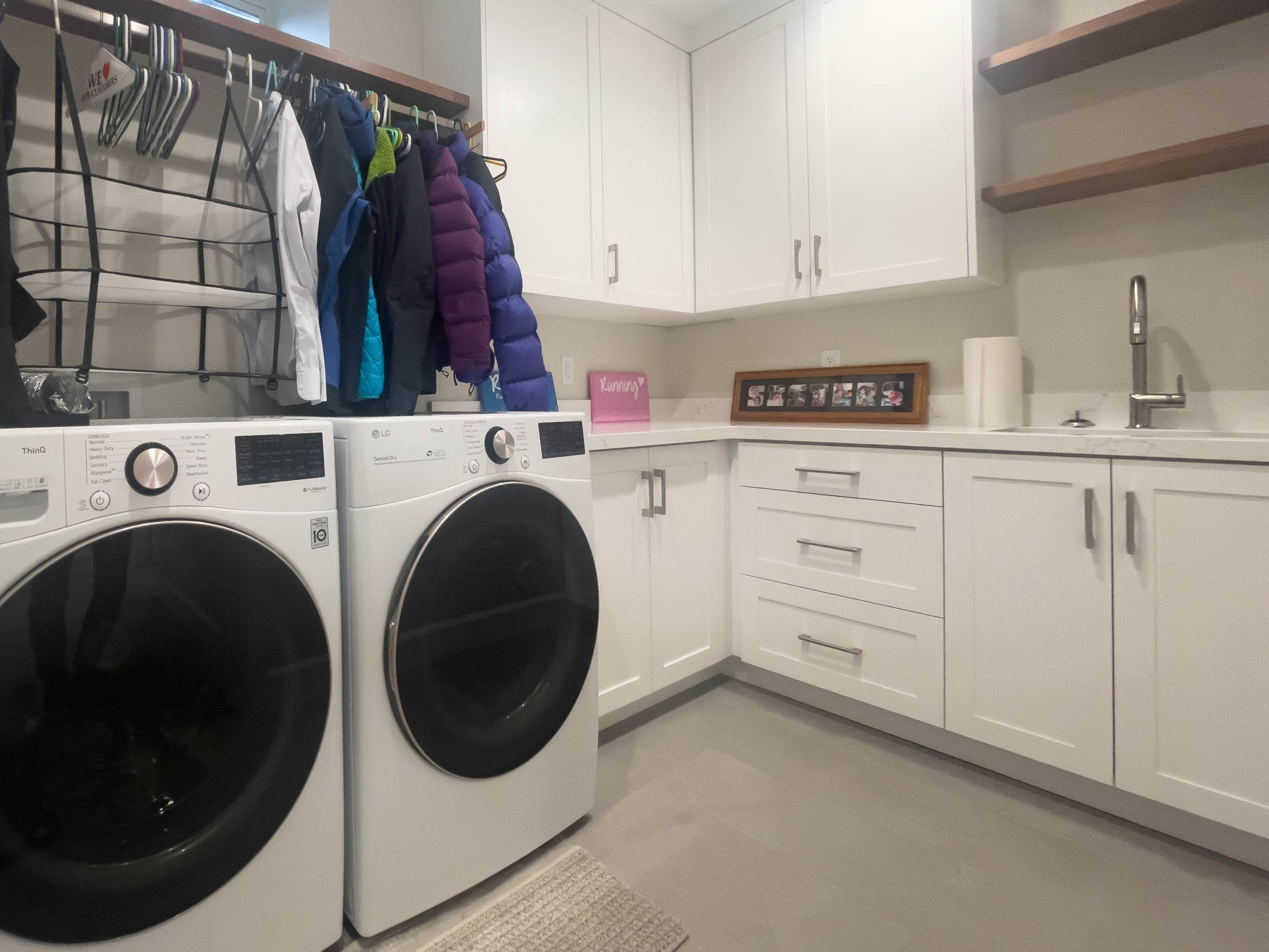 Laundry room with side-by-side washer and dryer, cabinetry, hanging rod, and a sink.