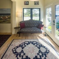 Thumbnail of http://Couch%20in%20front%20of%20a%20window%20with%20a%20rug%20centered%20in%20front%20and%20a%20door%20to%20the%20right.