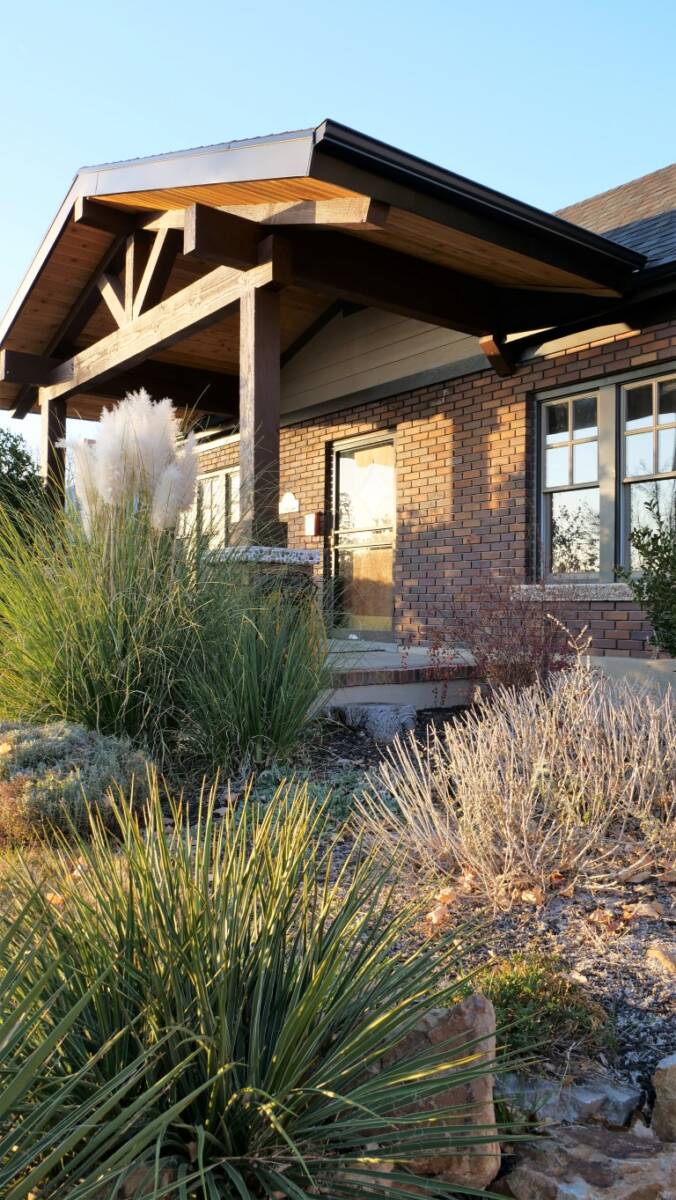 Front exterior renovation at a brick house featuring a covered front porch and new landscaping.