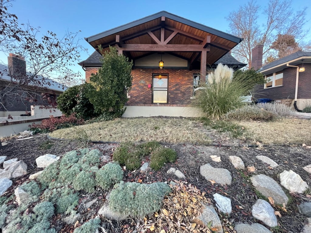 Front exterior renovation at a brick house featuring a covered front porch and new landscaping.