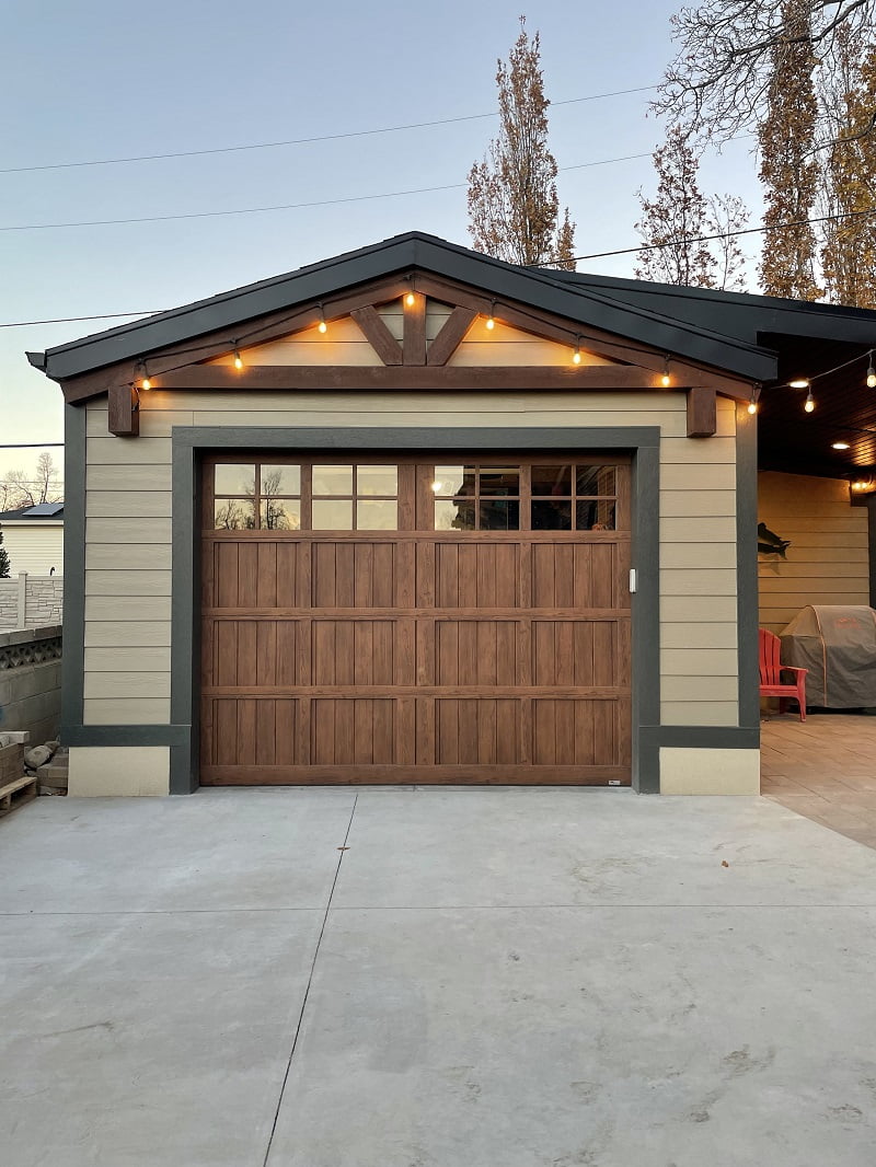 One-car garage exterior with a concrete driveway and string lights hung above.
