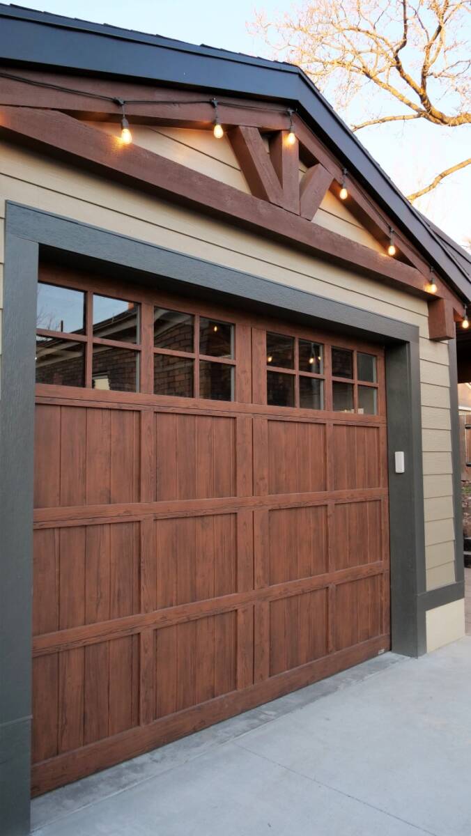 One-car garage exterior with a concrete driveway and string lights hung above.