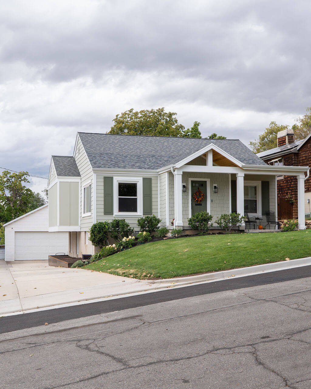 Front exterior of cottage style home. The yard is landscaped with grass and includes a path with access to the front porch.