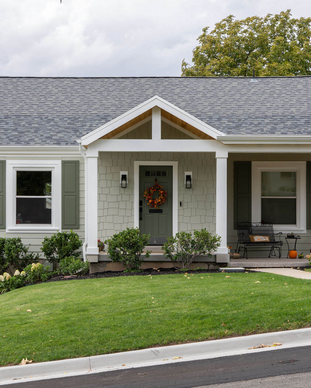 Front exterior of cottage style home. The yard is landscaped with grass and includes a path with access to the front porch.
