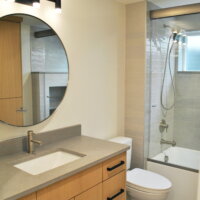 Thumbnail of http://Bathroom%20renovation%20with%20a%20sink,%20toilet,%20and%20combined%20tub%20and%20shower.%20The%20sink%20has%20cabinets%20and%20drawers%20underneath%20and%20a%20round%20mirror%20and%20light%20fixture%20hung%20above.