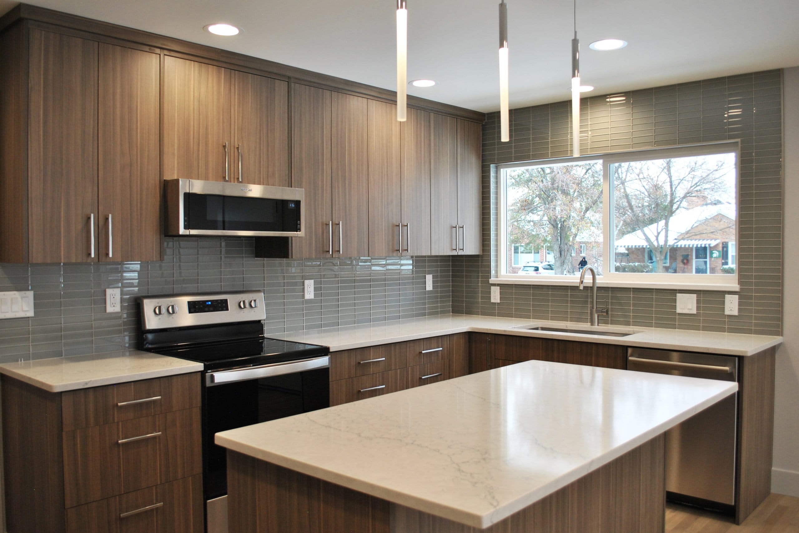 Kitchen with an island, dark cabinetry, and a large window above the sink.