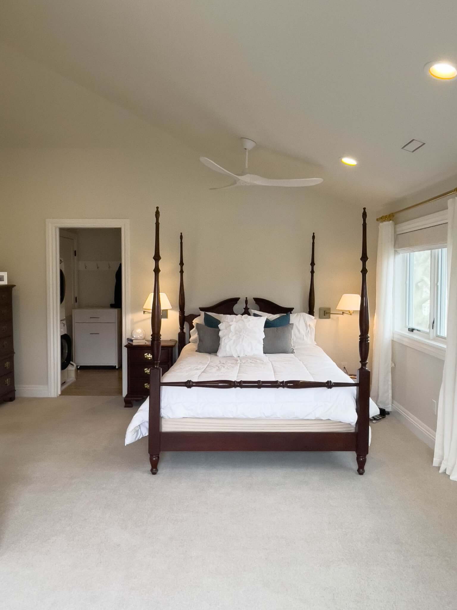 Primary bedroom with a bed under the ceiling fan, vaulted ceilings, curtains hung on the windows, and a door with access to the closet.