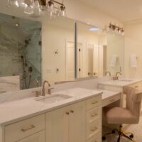 Thumbnail of http://Primary%20bathroom%20vanity.%20The%20vanity%20includes%20two%20sinks%20with%20a%20makeup%20vanity%20between,%20Above%20the%20sinks%20are%20large%20mirrors%20and%20light%20fixtures.