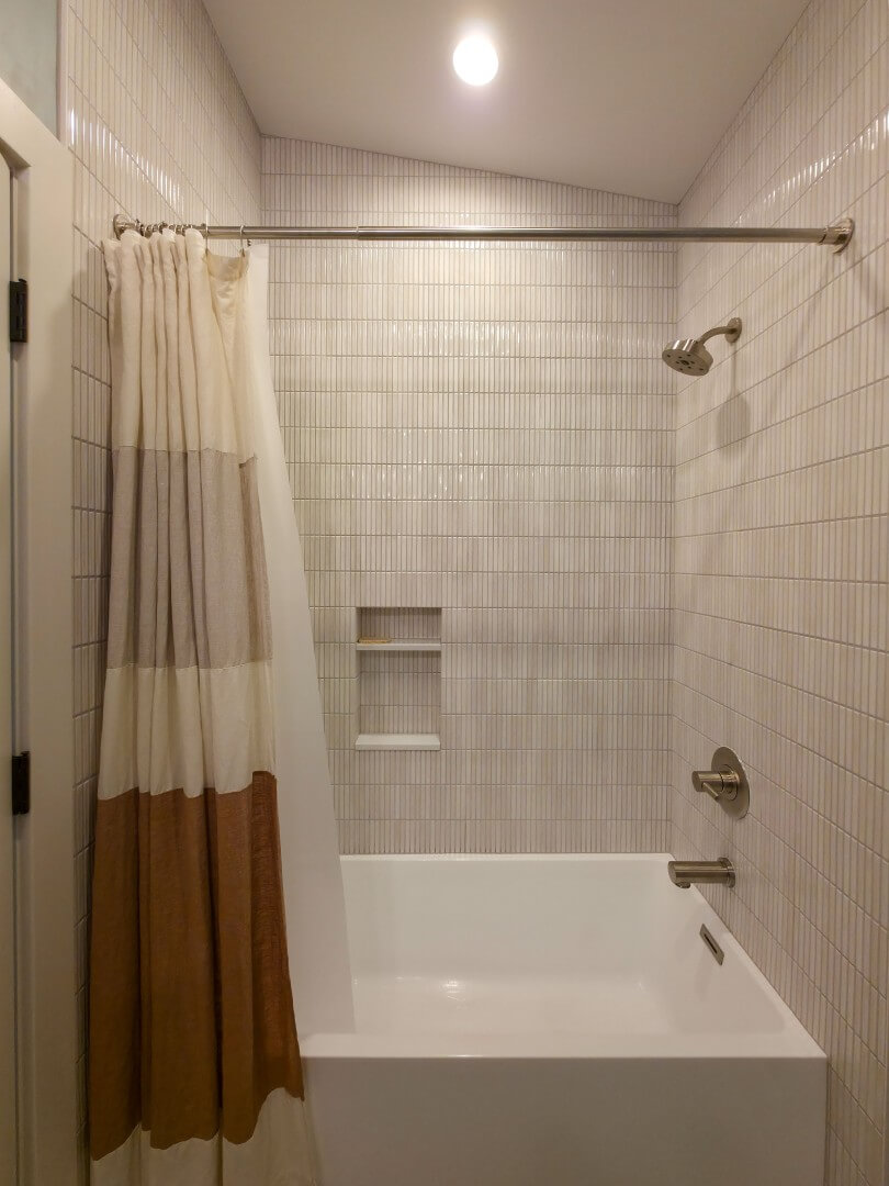 Guest bathroom tub with a simple, elegant design. The combined tub and shower includes a niche.