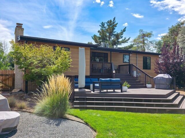 Large backyard deck that is multiple levels. The deck extends from the house and down to the grass in the yard.