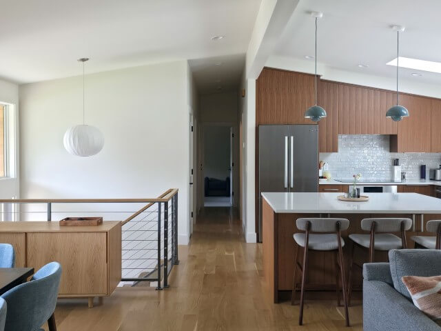 Open concept mid-century modern design following the renovation. On the left are the stairs to the front door and basement. On the right is the kitchen.