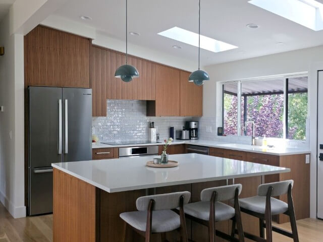 Mid-century modern kitchen renovation featuring vaulted ceilings and an island in the center.