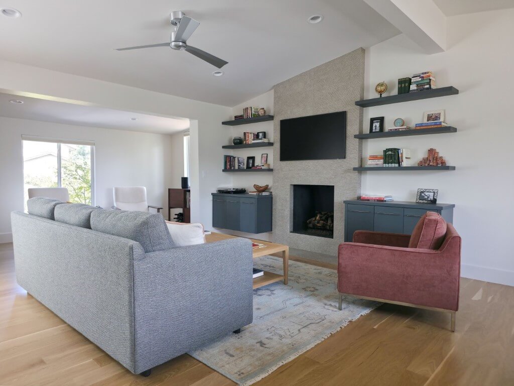 Renovated living room in a mid-century modern design. The space features a fireplace with built-in shelves on either side.