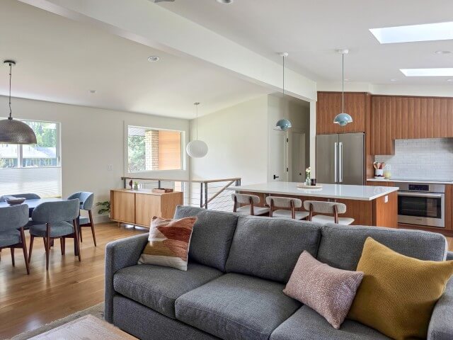 Open concept living room, dining room, and kitchen after the renovation. The space features vaulted ceilings and lots of natural light.