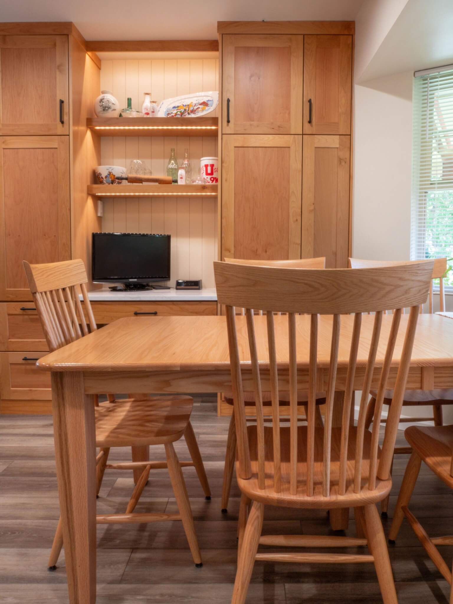 Dining table with chairs and a cabinet behind.