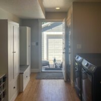 Thumbnail of http://Combined%20mudroom%20and%20laundry%20room%20with%20washer%20and%20dryer%20placed%20side-by-side%20to%20the%20right%20and%20cabinets%20to%20the%20left.%20Door%20to%20the%20backyard%20is%20open%20showing%20the%20patio%20furniture%20in%20front%20of%20the%20garage.