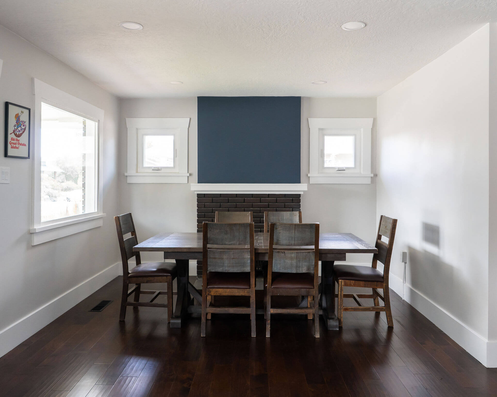 Renovated dining room with a large table, windows, and fireplace.