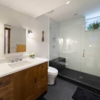 Thumbnail of http://Bathroom%20with%20shower,%20toilet,%20and%20large%20sink.%20The%20shower%20includes%20a%20windowsill%20where%20a%20plant%20is%20as%20well%20as%20a%20niche%20and%20bench.%20The%20sink%20includes%20a%20mirror%20with%20lights%20hung%20on%20either%20side%20and%20storage%20below.