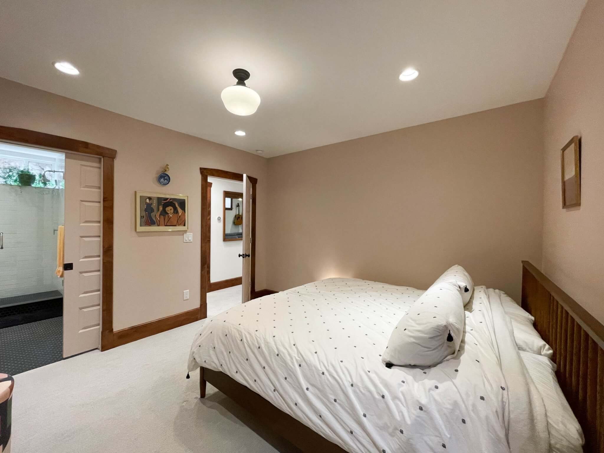 Large basement bedroom with bed, door with access to the hallway, and a pocket door with access to the bathroom.