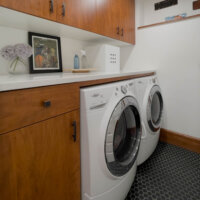 Thumbnail of http://Laundry%20room%20with%20tile%20on%20the%20floor%20and%20cabinets%20around%20the%20side-by-side%20washer%20and%20dryer.