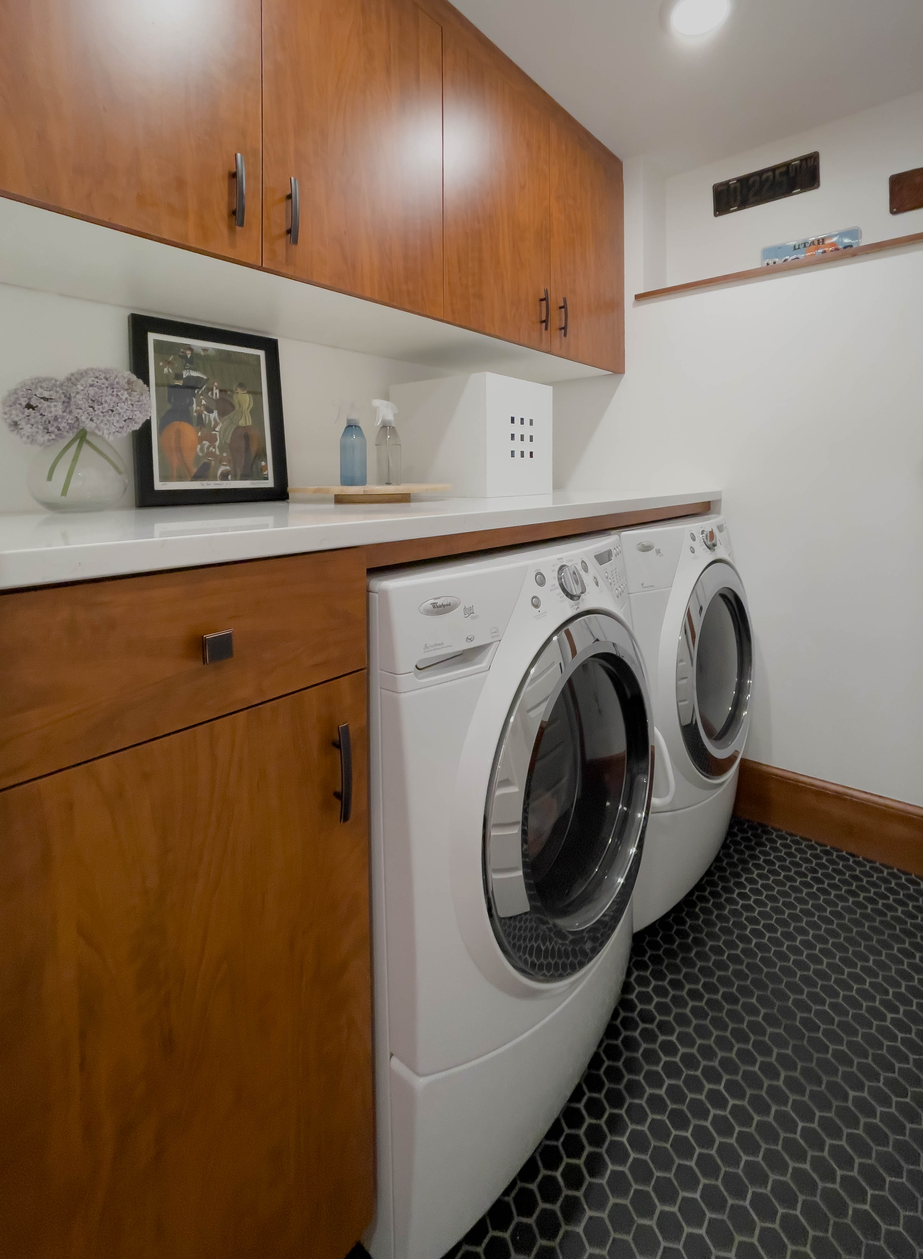 Laundry room with tile on the floor and cabinets around the side-by-side washer and dryer.