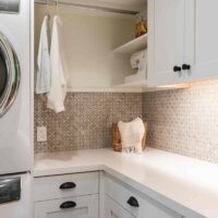Thumbnail of http://Laundry%20room%20cabinetry%20with%20a%20stacked%20washer%20and%20dryer%20and%20hanging%20rod%20to%20the%20side.