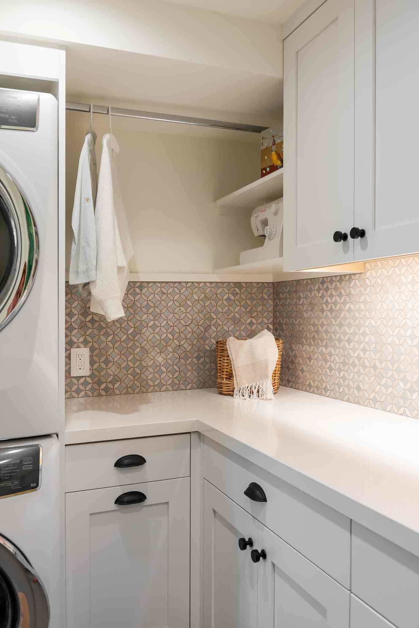 Laundry room cabinetry with a stacked washer and dryer and hanging rod to the side.