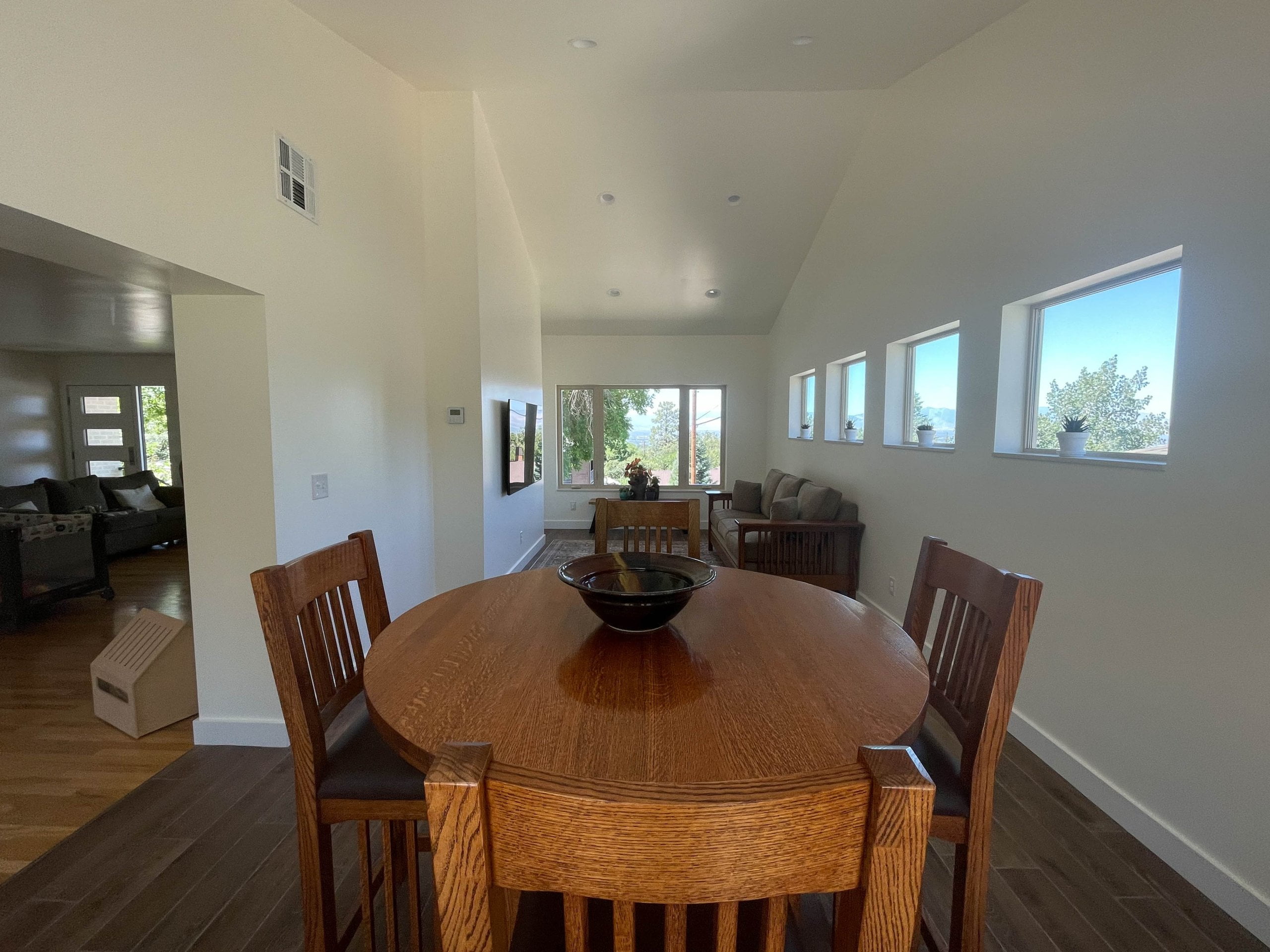 Interior of the addition. The space includes vaulted ceilings, multiple windows, a table and chairs, and a couch with a rug in front of the TV.