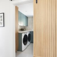 Thumbnail of http://Wood%20barn%20door%20part%20way%20open%20with%20view%20into%20the%20large%20laundry%20room.%20The%20laundry%20room%20features%20cabinetry%20painted%20in%20a%20fun%20color,%20a%20folding%20counter%20above%20the%20side-by-side%20washer%20and%20dryer,%20and%20a%20spacious%20layout.