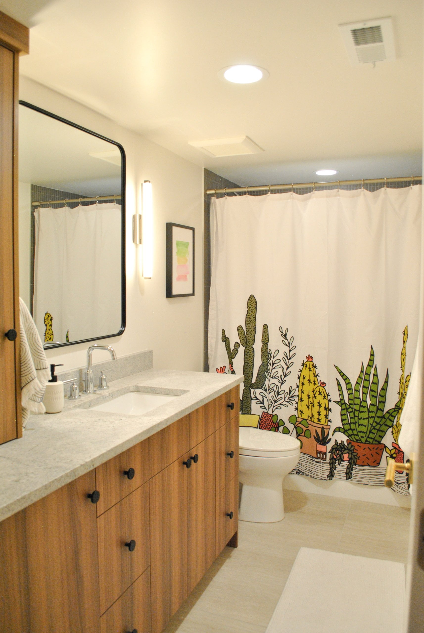 Bathroom with a shower curtain hung, toilet, and large vanity with storage.