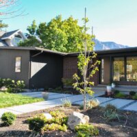 Thumbnail of http://Mid-century%20modern%20house%20exterior%20with%20a%20covered%20front%20porch,%20new%20landscaping,%20and%20large%20windows.