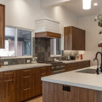 Thumbnail of http://Contemporary%20kitchen%20design%20with%20a%20galley%20layout%20that%20is%20partially%20open%20to%20the%20living%20room.%20The%20kitchen%20includes%20windows%20on%20either%20side%20of%20the%20stove,%20vaulted%20ceilings,%20and%20a%20range%20with%20a%20hood%20above.