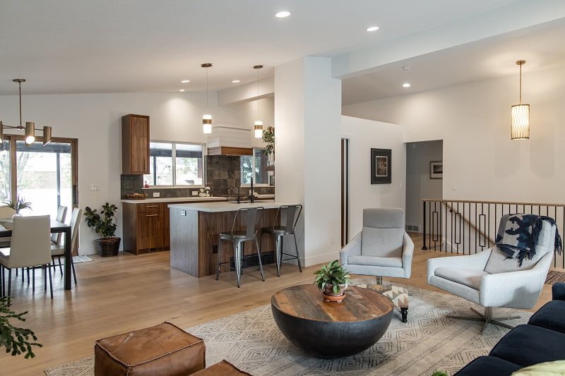 Open concept contemporary great room with vaulted ceilings. The living room is open to the entry, dining room, and partially to the kitchen. The part of the kitchen that is open incudes a peninsula with two bar stools.