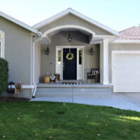Thumbnail of http://Stucco%20home%20with%20a%20covered%20front%20porch%20and%20concrete%20steps%20down%20to%20the%20driveway,%20two-car%20garage,%20and%20green%20lawn.