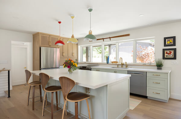 Custom kitchen remodel featuring a colorful design, open concept layout, and lots of storage. An island is in the center with seating for three.